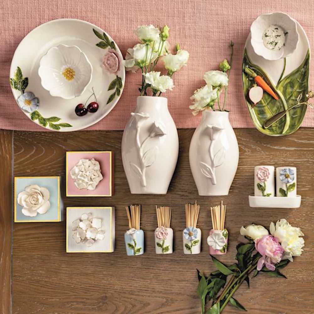 An assortment of floral-themed ceramic tableware, vases, and toothpick holders arranged on a wooden surface.