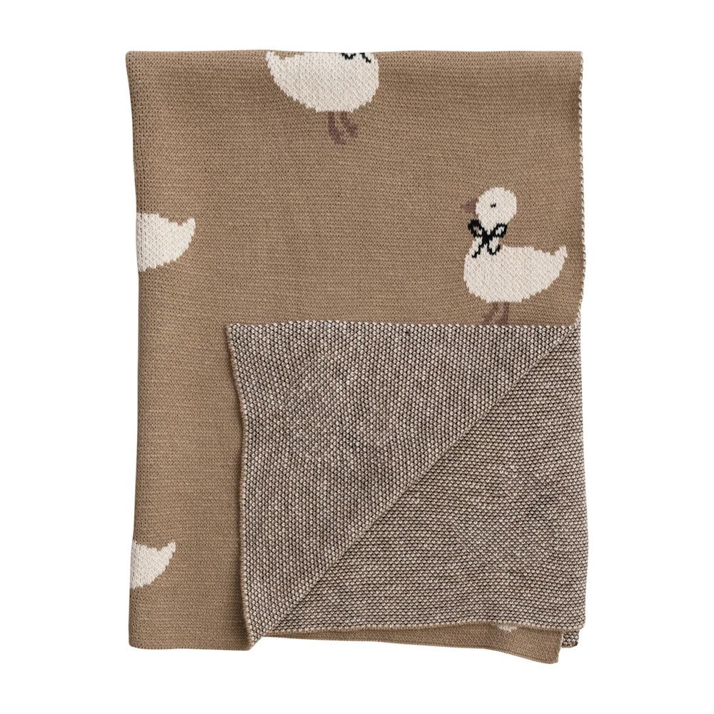 Folded brown cotton knit baby blanket showing white ducklings with black bows and a textured underside.