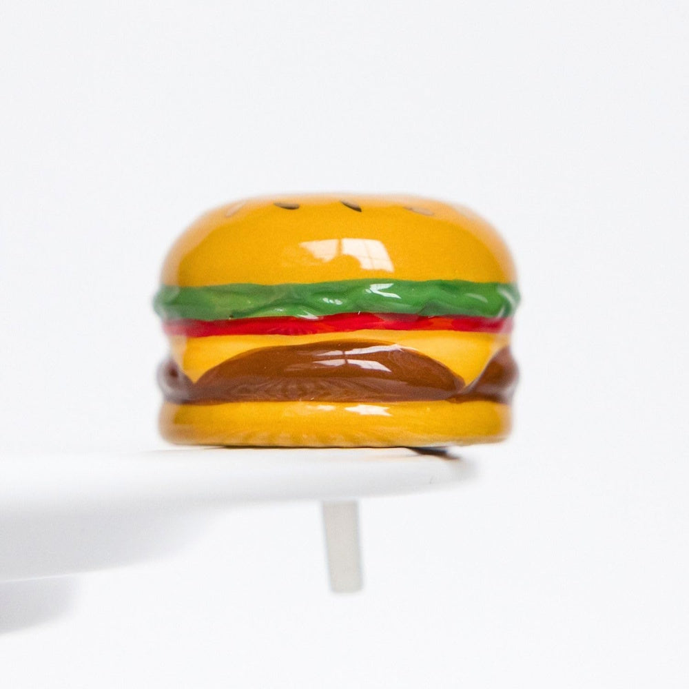 Miniature hamburger-shaped ceramic knob with lettuce, cheese, and tomato details on a white surface.