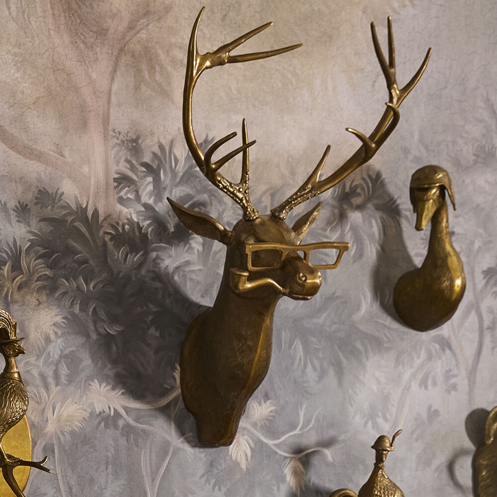 Brass deer head wall mount with large antlers, wearing thick-rimmed glasses and holding a pipe in its mouth.