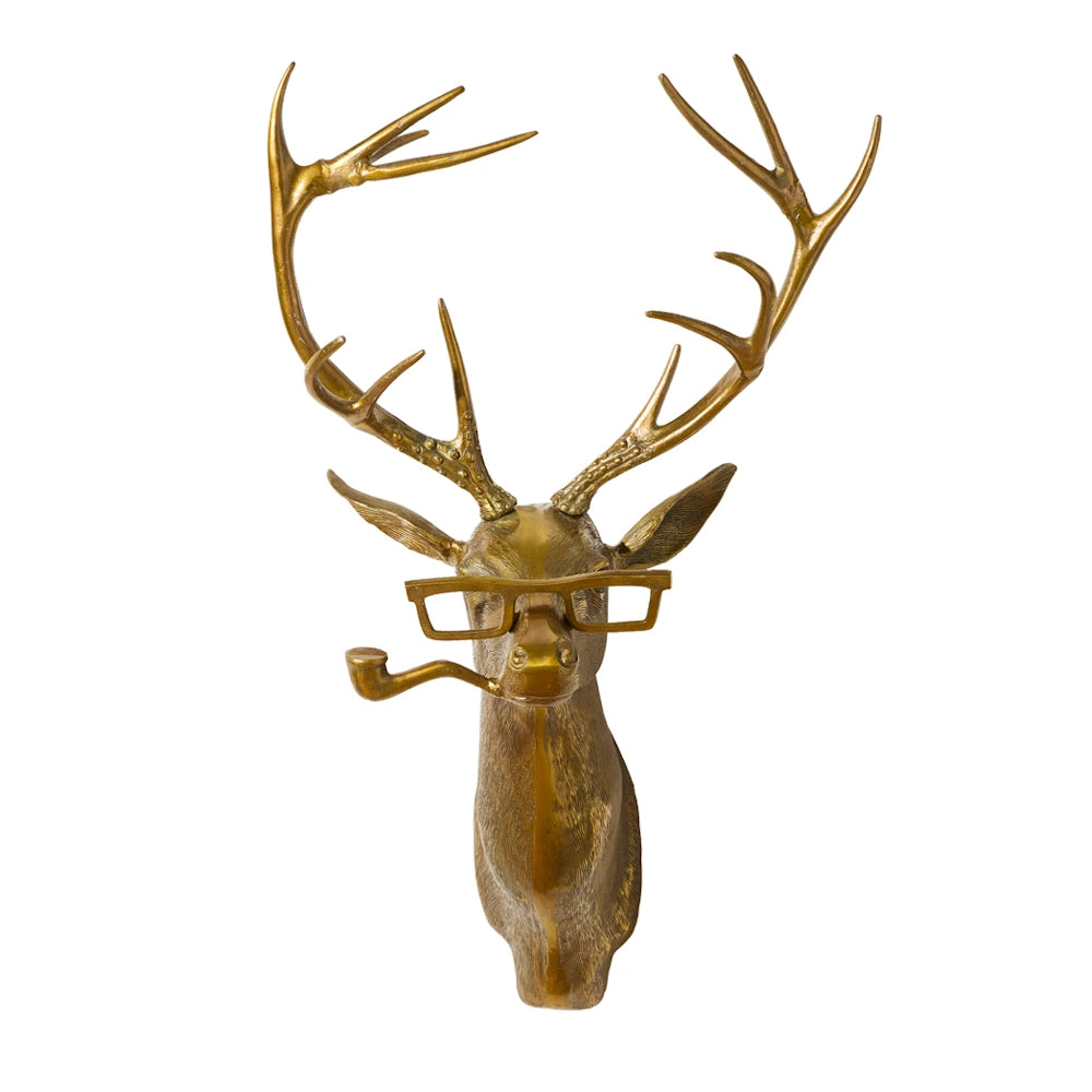 A brass stag head wall mount with large antlers, wearing thick-rimmed glasses and holding a pipe in its mouth.