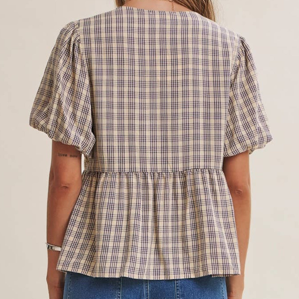 Back view of a plaid babydoll blouse featuring short bubble sleeves and a gathered peplum hem.