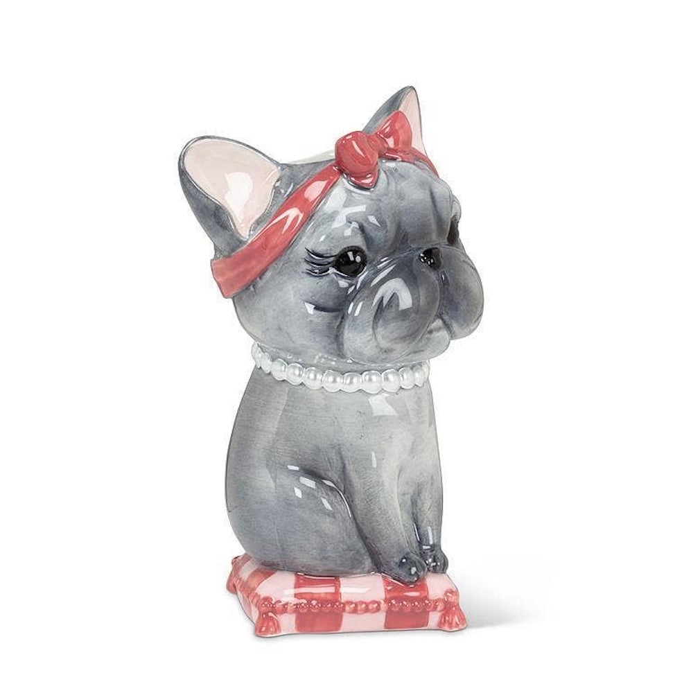 Ceramic French bulldog vase wearing a red headband bow and pearl necklace, sitting on a cushion.