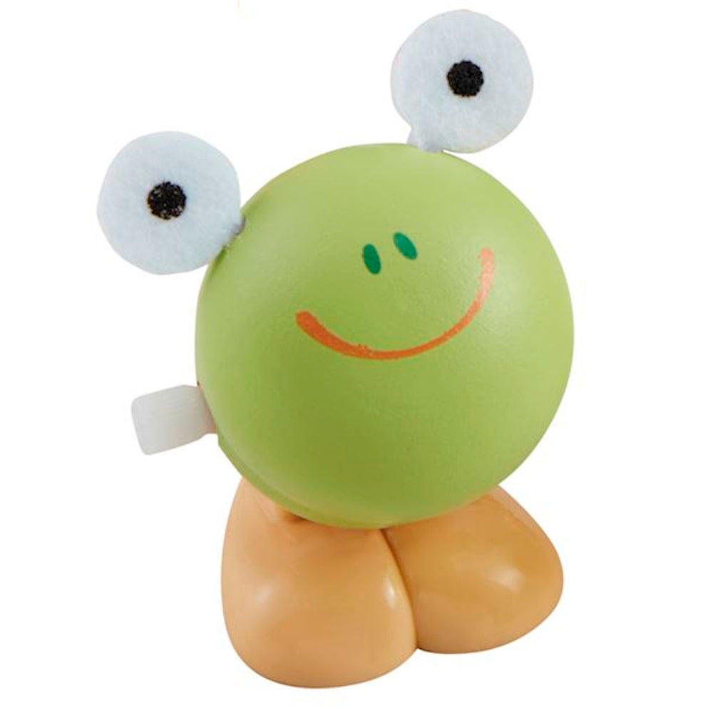 Wooden wind-up frog toy with a round green head, large white eyes, orange smile, and tan legs on a white background.