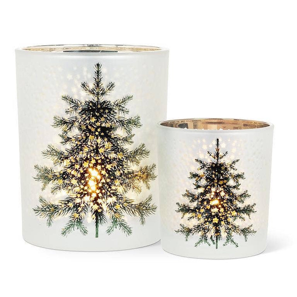 Two frosted glass candle holders with illuminated Christmas tree designs and starry accents.