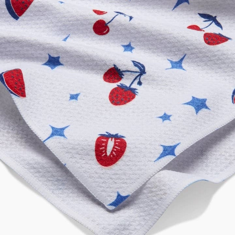 White fabric with a pattern of red strawberries, watermelons, cherries, and blue stars.