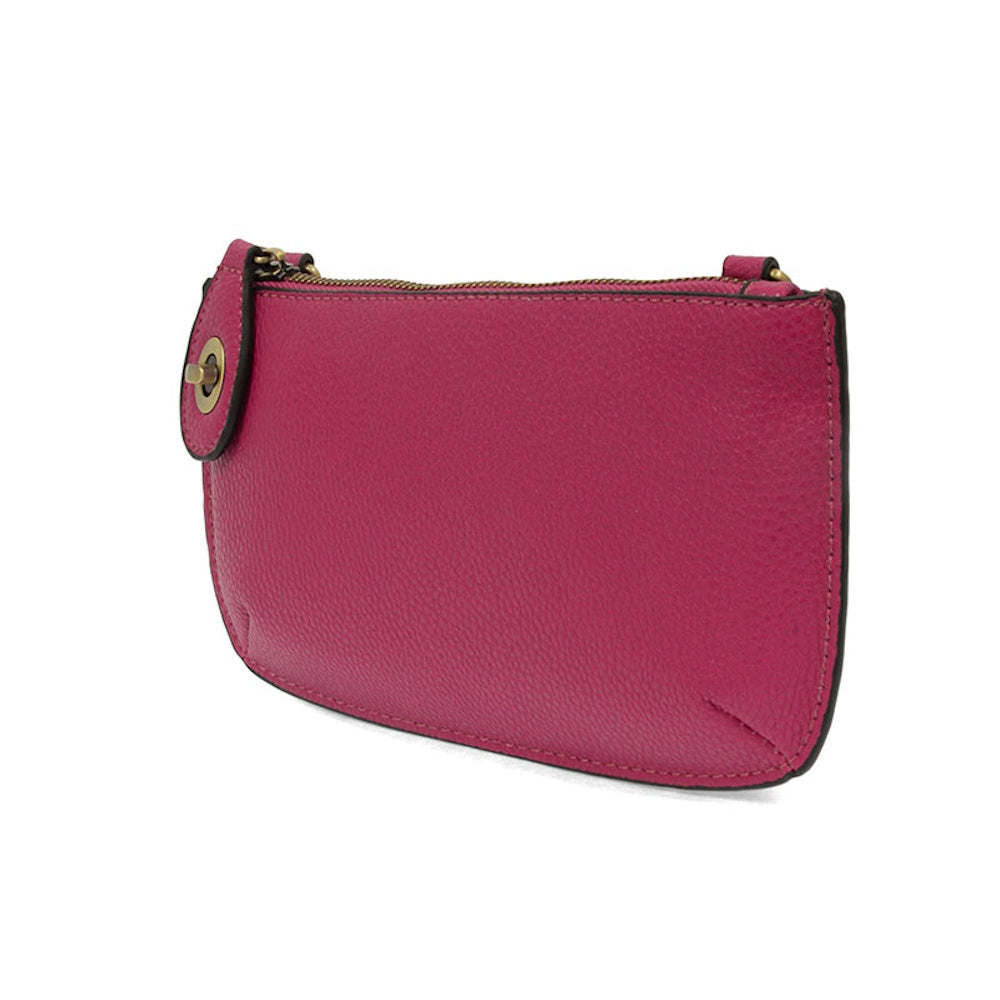 Fuchsia pink leather mini crossbody clutch bag with gold-tone hardware and zipper closure on a white background.