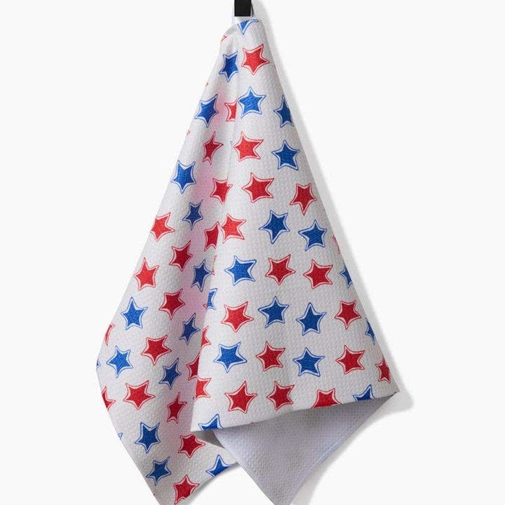 White tea towel with a waffle texture featuring an all-over pattern of small red and blue five-pointed stars.