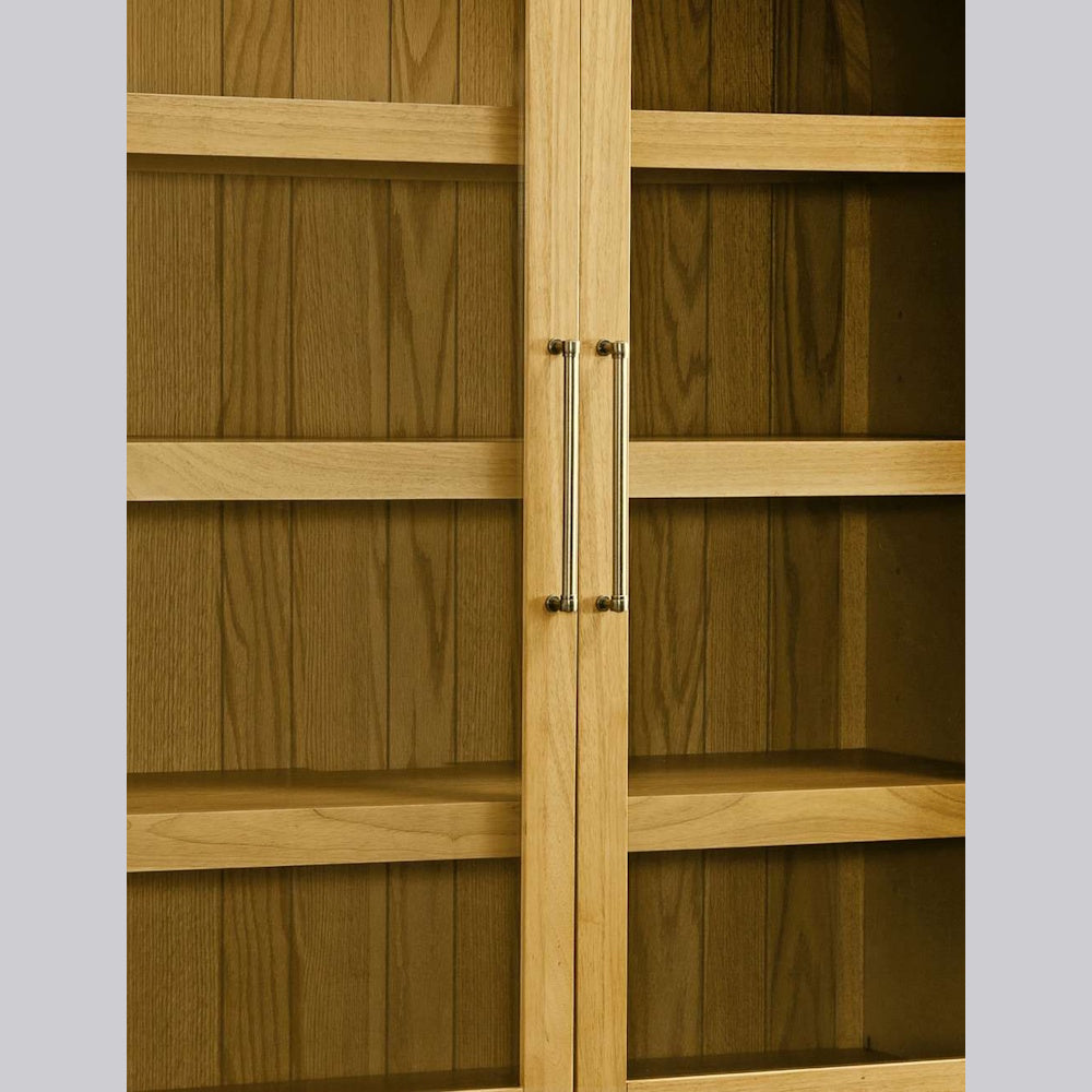 Oak wood display cabinet with glass doors, internal shelving, and slim brass handles.