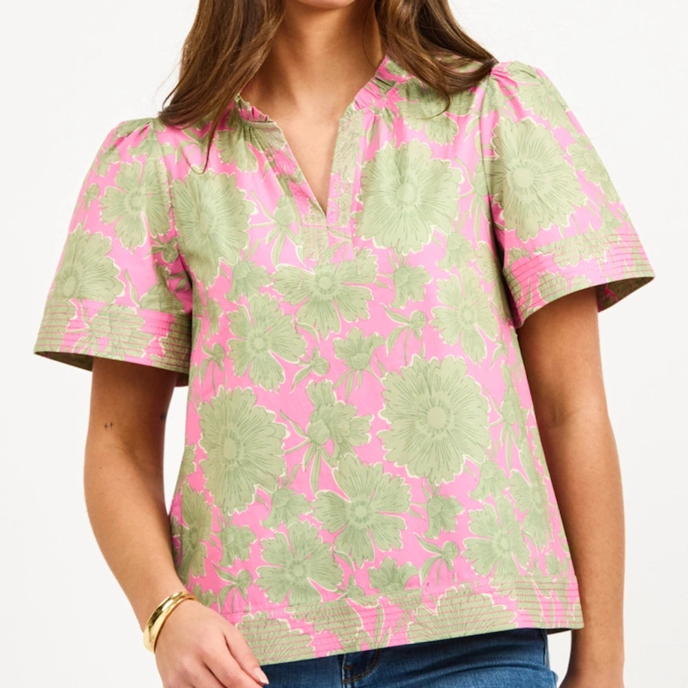 Woman wearing a pink and green floral short sleeve top with a v-neckline.