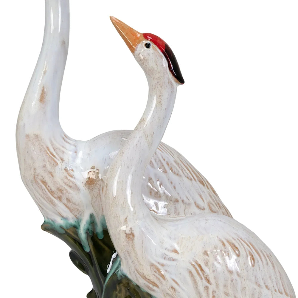 A ceramic figurine of two white red-crowned cranes with long necks, gazing upward against a plain background.