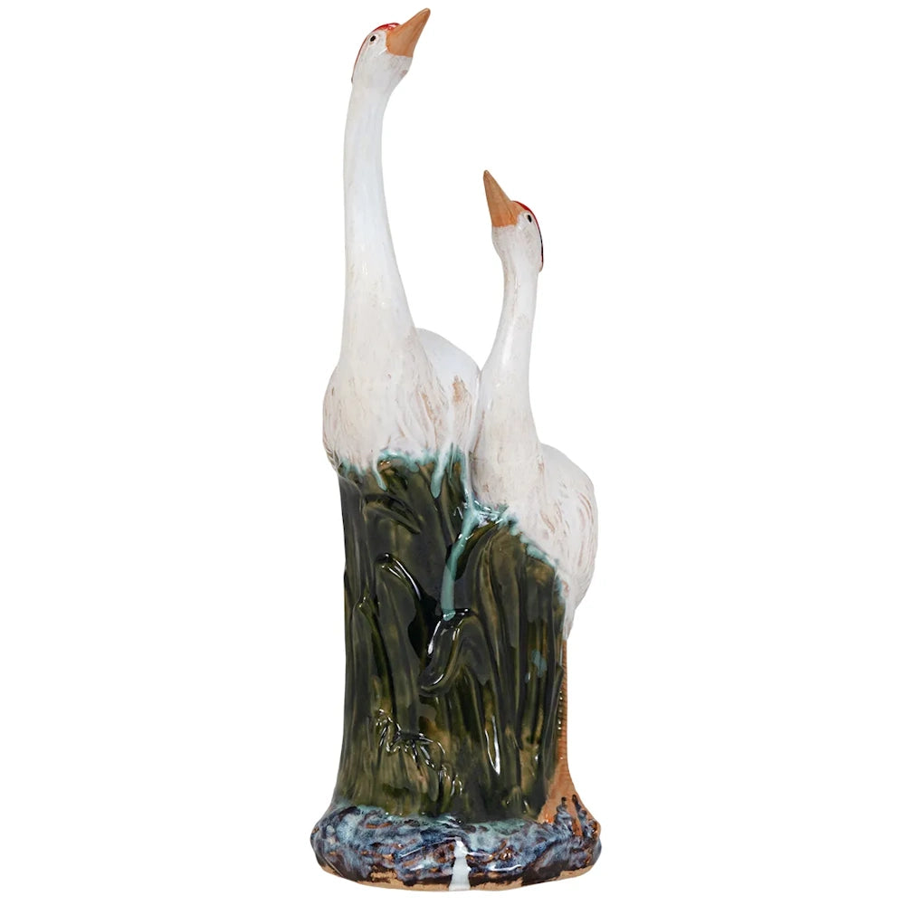 Front view of a glazed ceramic figurine featuring two white cranes with red crowns gazing upward.
