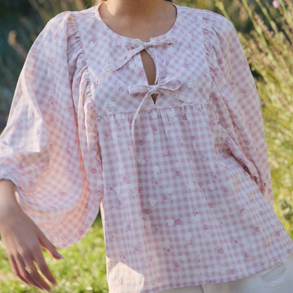 Pink and white gingham blouse with floral embroidery, puff sleeves, and double tie-front keyhole closure.
