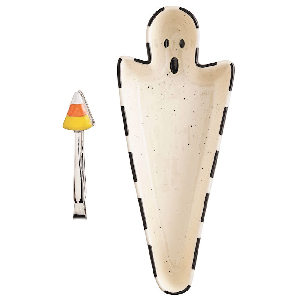 Ghost-shaped Halloween sweets dish with black trim alongside candy corn topped serving tongs.