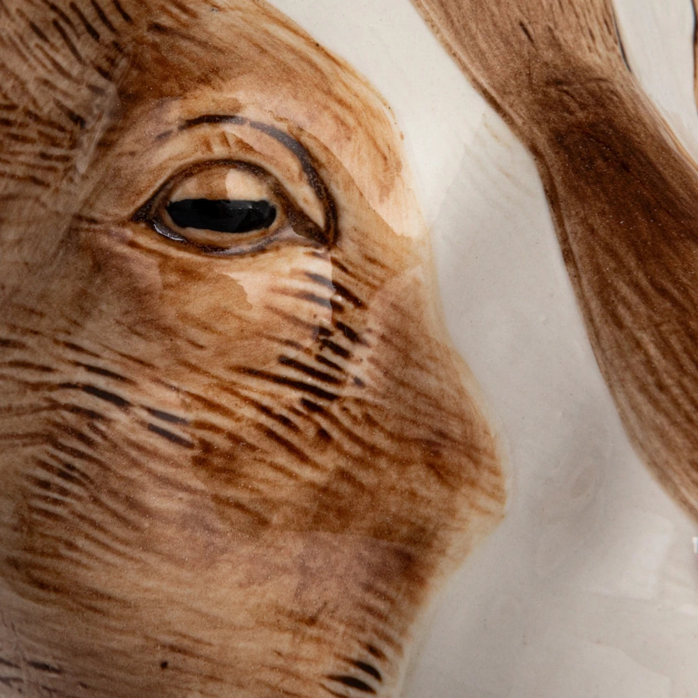 Close-up of hand-painted brushstrokes on a goat-shaped stoneware vase, detailing the eye and brown textured finish.