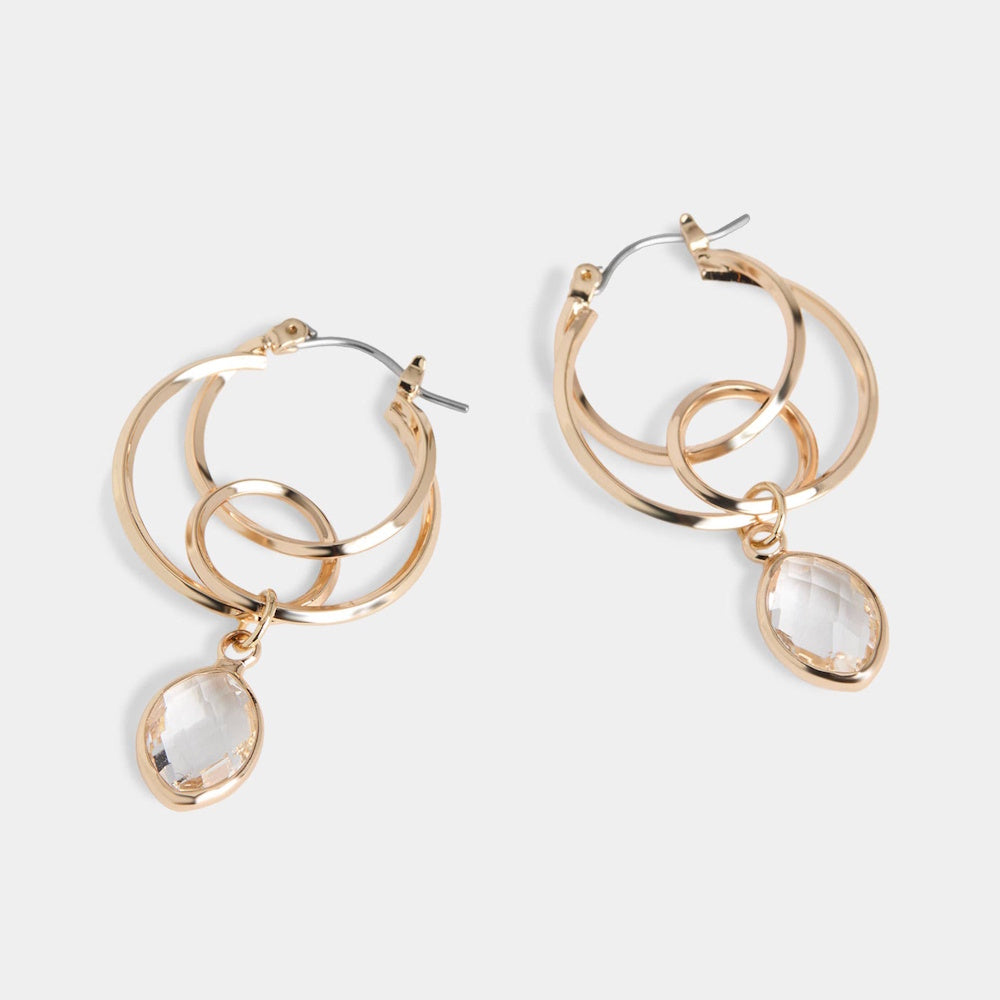 Layered gold hoop earrings featuring a dangling clear faceted crystal drop charm.