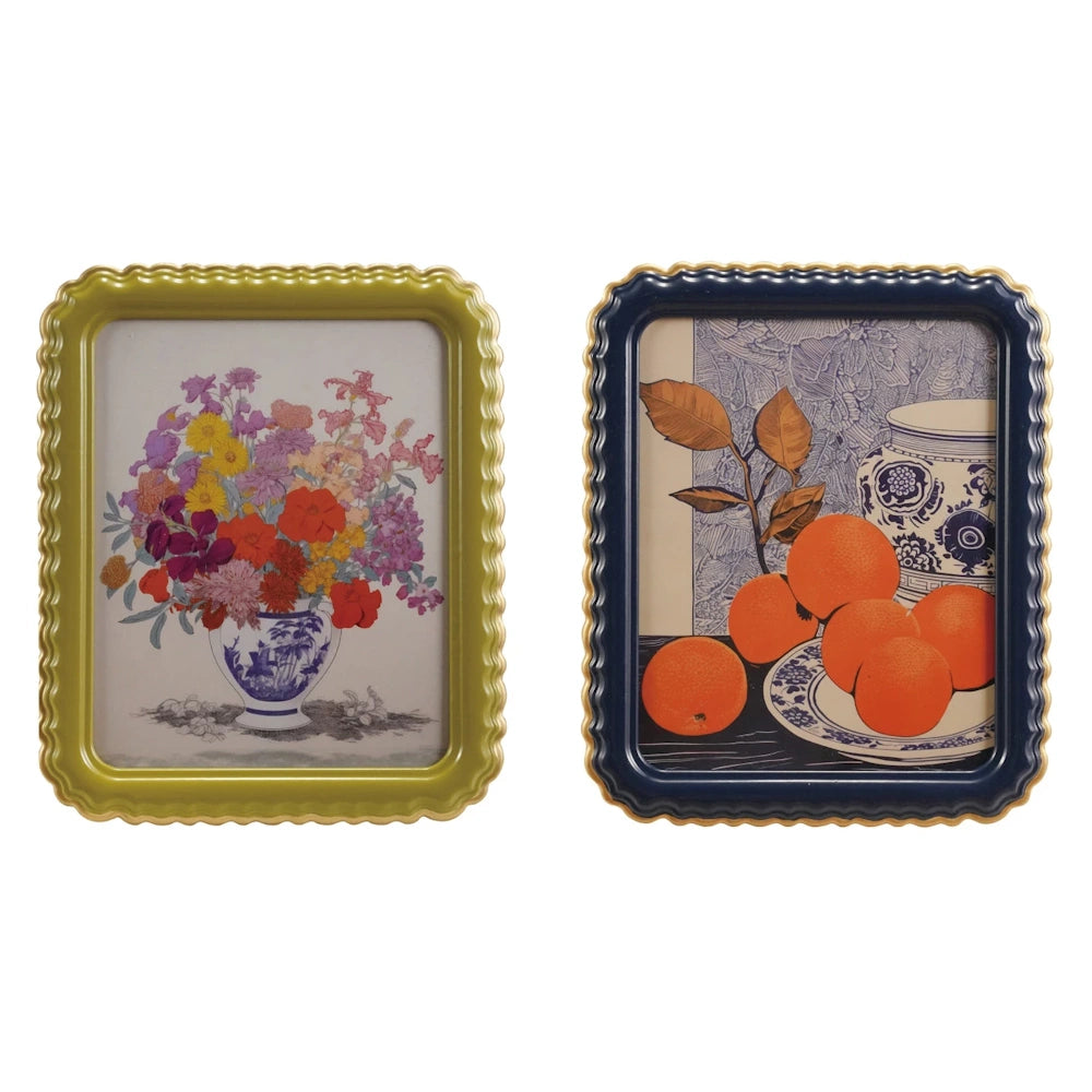 Green and navy blue scalloped picture frames with gold edges, showcasing floral and orange fruit still life art prints.