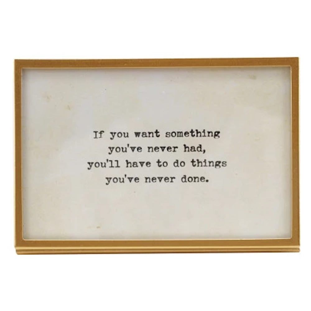 Gold metal and glass picture frame featuring an inspirational quote in a typewriter-style font on a white background.