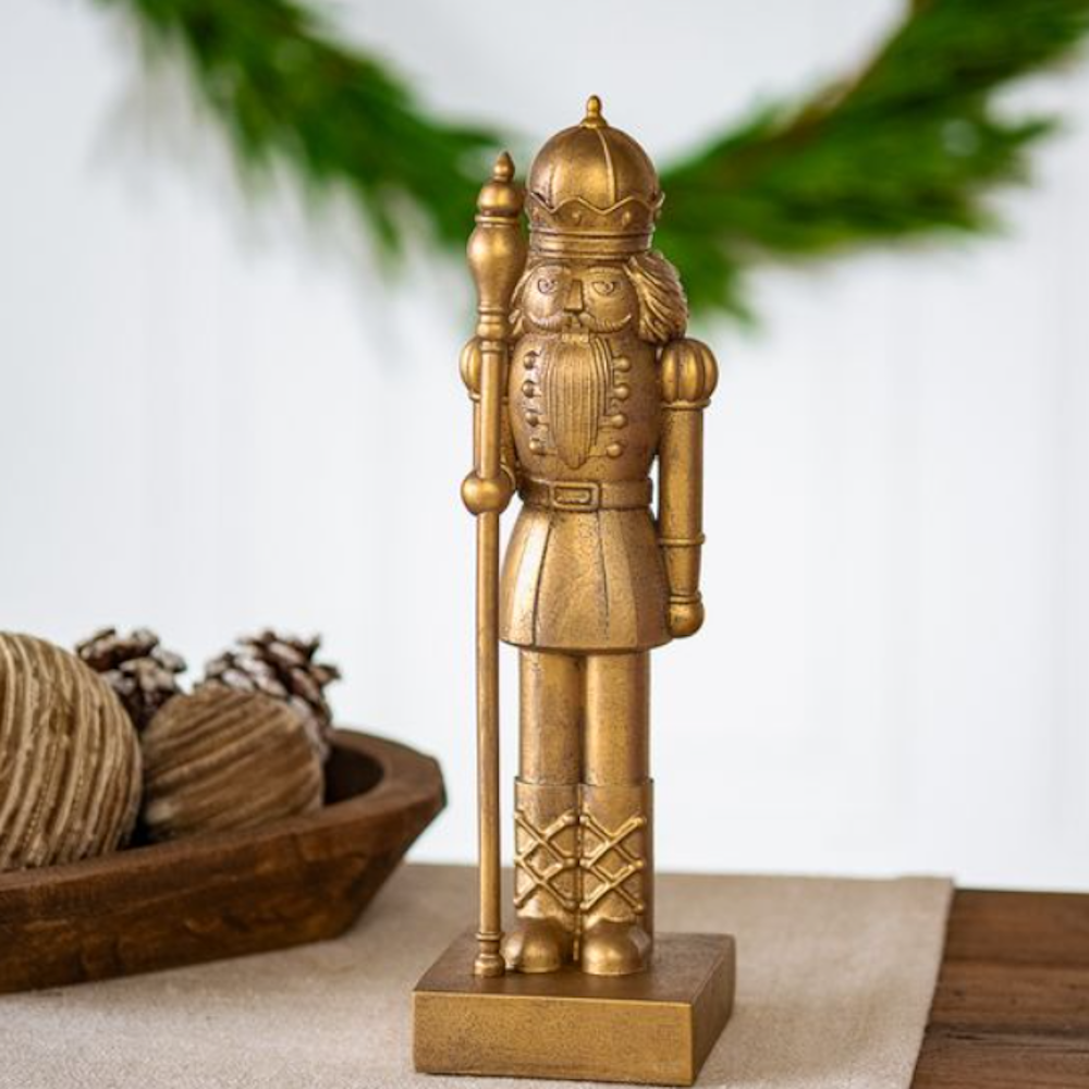 Gold nutcracker figurine standing on a square base with a decorative staff.