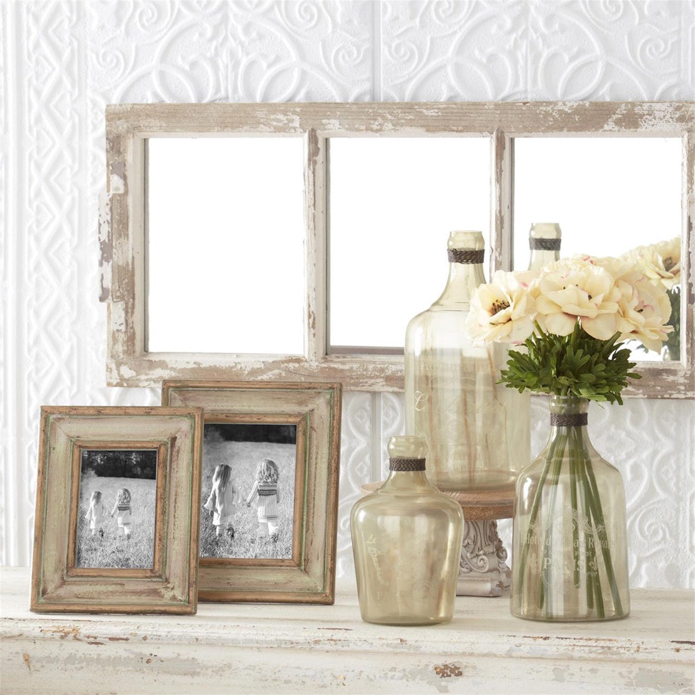 Green and gold patina wood photo frames with glass vases and flowers on a distressed white mantel.
