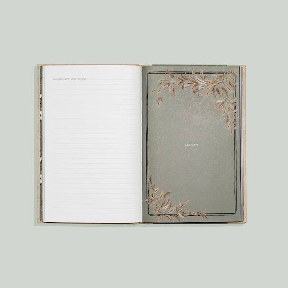 Open memory journal with a lined page for writing and a decorative green page with leaf accents for adding a photo.