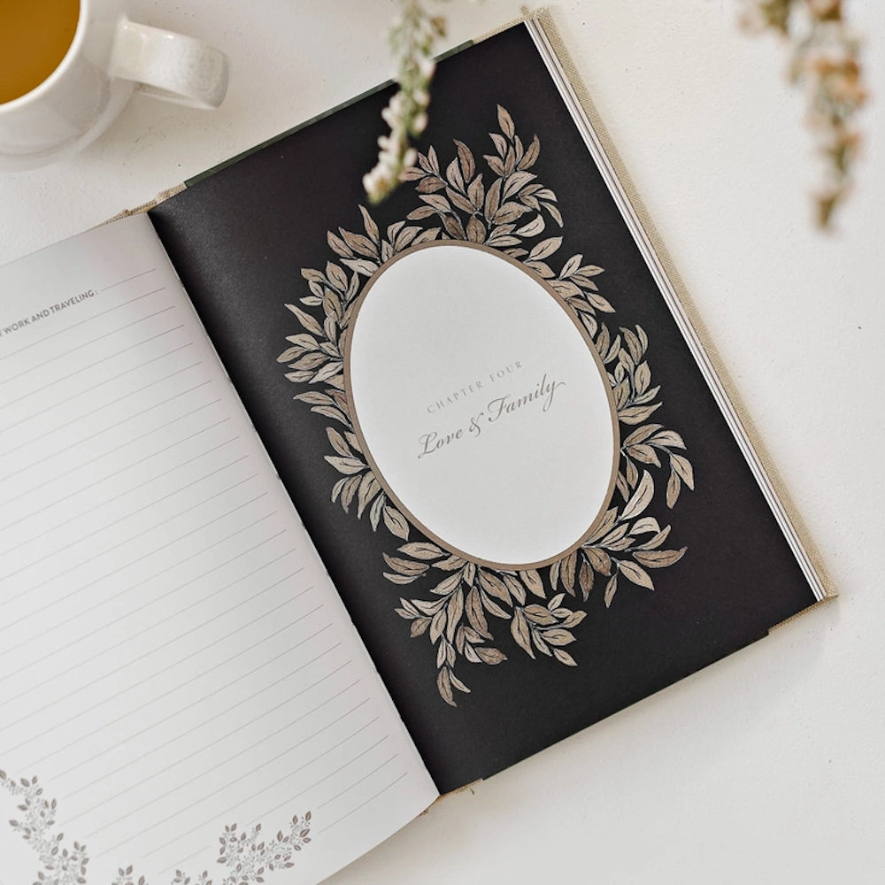 Open keepsake journal showing Chapter Four: Love and Family page with an elegant leaf border and lined memory pages.