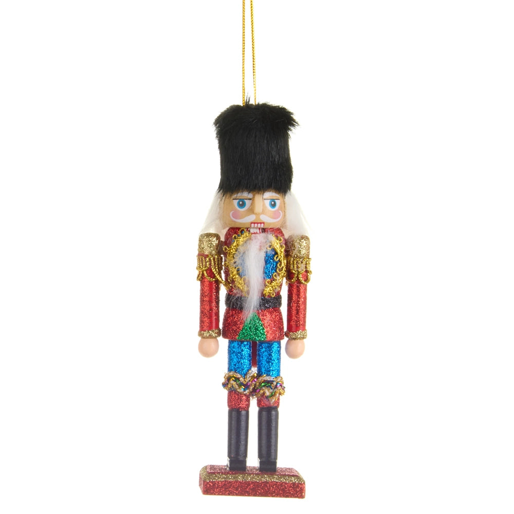 Glittering nutcracker Christmas tree ornament wearing a tall black hat, red jacket, and green belt.