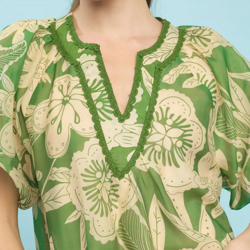 Green and cream floral v-neck top with scalloped trim and puff sleeves.