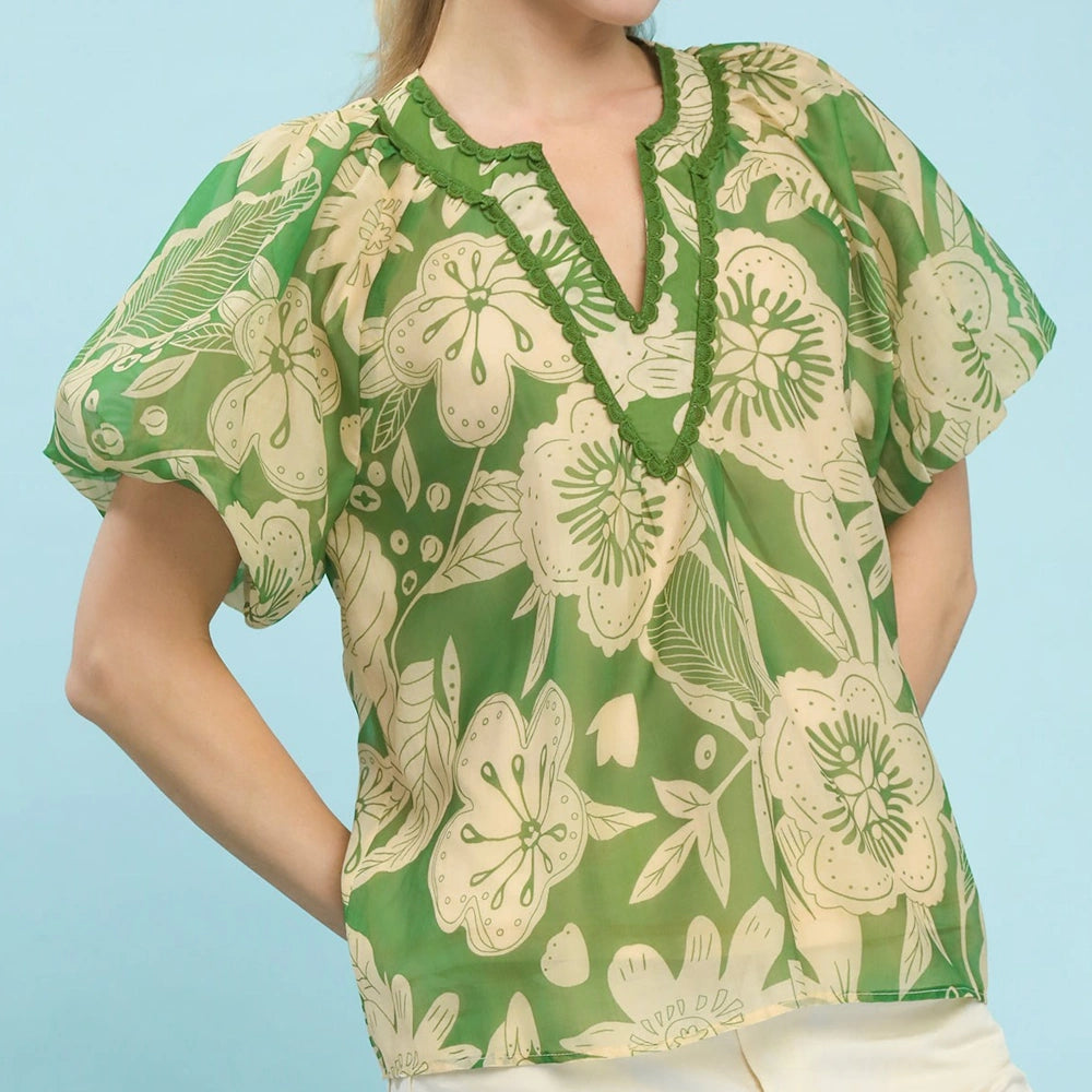 Green and cream floral V-neck top with puff sleeves and scalloped trim detailing.