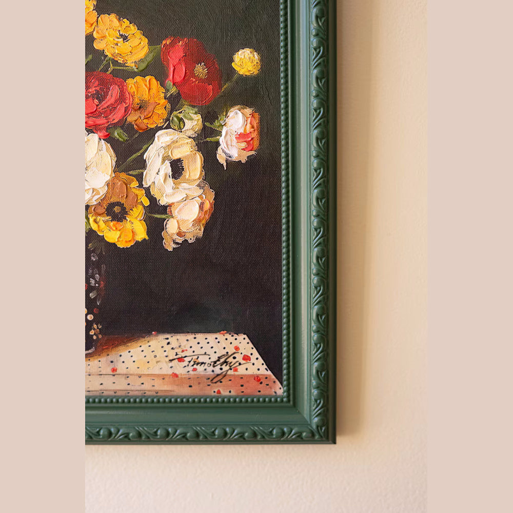 Close-up of a floral oil painting with thick impasto texture in an ornate dark green frame against a beige wall.