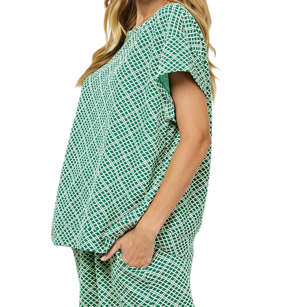 A woman stands in profile wearing a green and white checkered short-sleeve top and matching high-waisted pants.