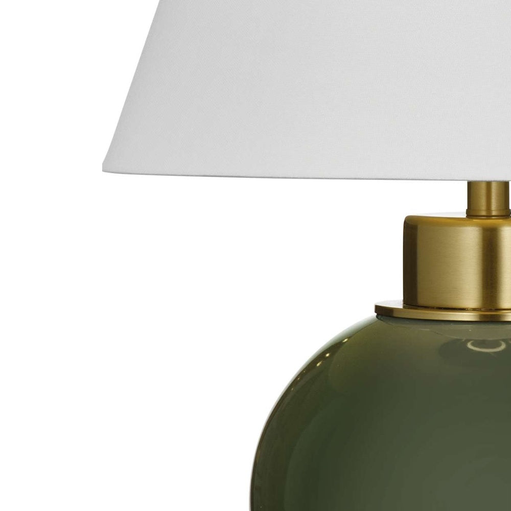 Close-up view of a white fabric lamp shade attached to a brushed brass socket above an olive green glass base.