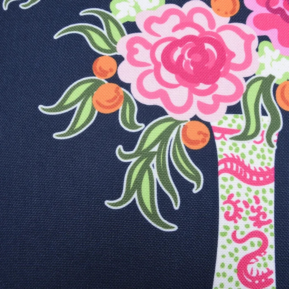 Pink floral pattern with green leaves and orange fruit on a dark navy blue canvas textured fabric background.