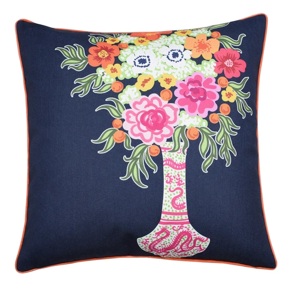 Navy blue throw pillow with a colorful floral bouquet in a patterned white vase and orange piped edges.