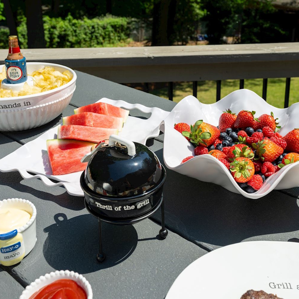Summer BBQ table spread with fruit, chips, and a mini grill condiment holder.