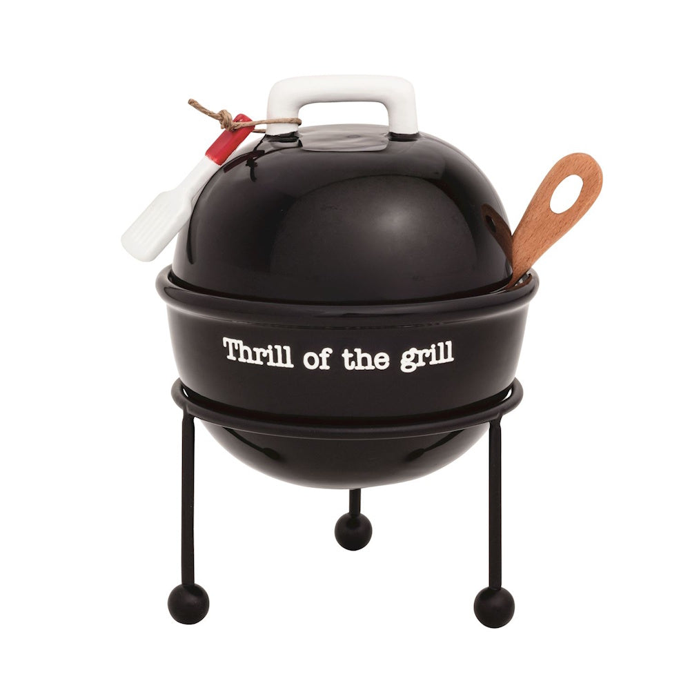 Black ceramic grill-shaped tidbit dish with "Thrill of the grill" text, lid, stand, and small utensils.