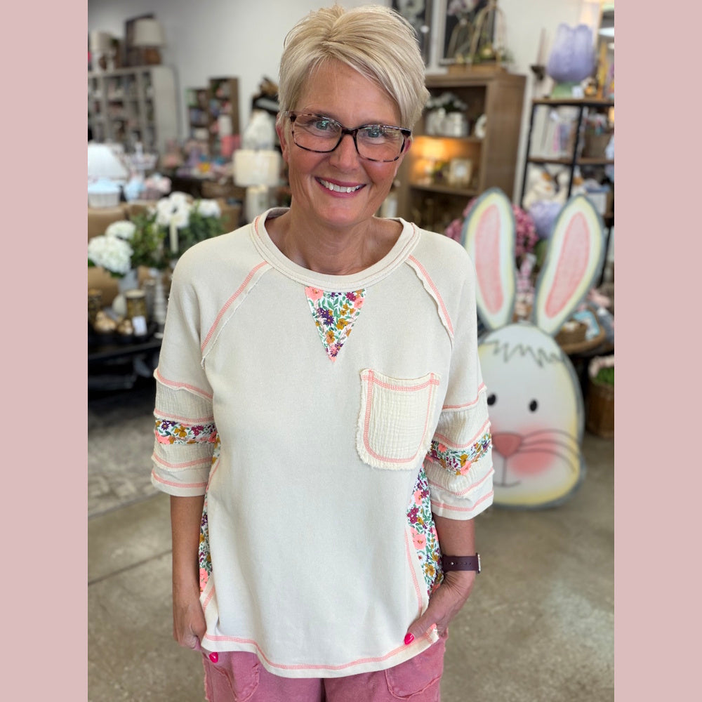 Woman wearing a patterned shirt in a store setting with decorative items.