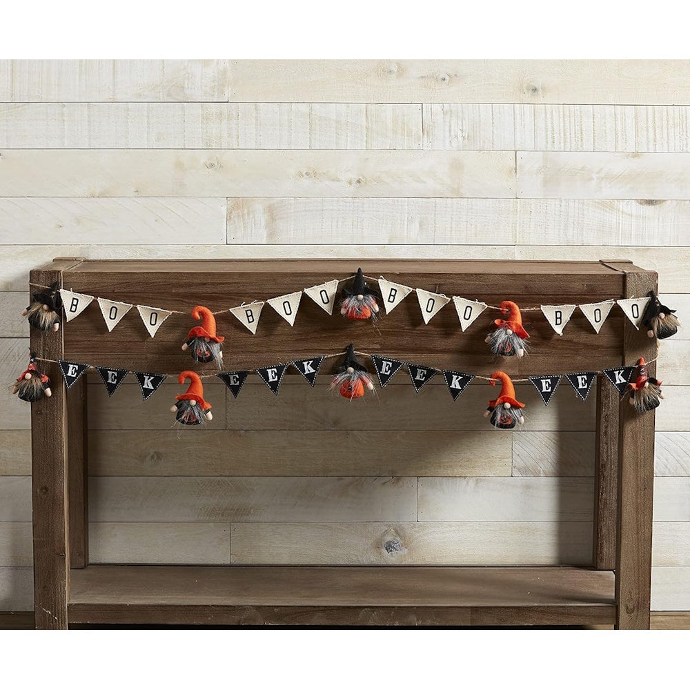 Halloween banner garlands reading "BOO" and "EEK" with plush gnomes hanging on a wooden console table.
