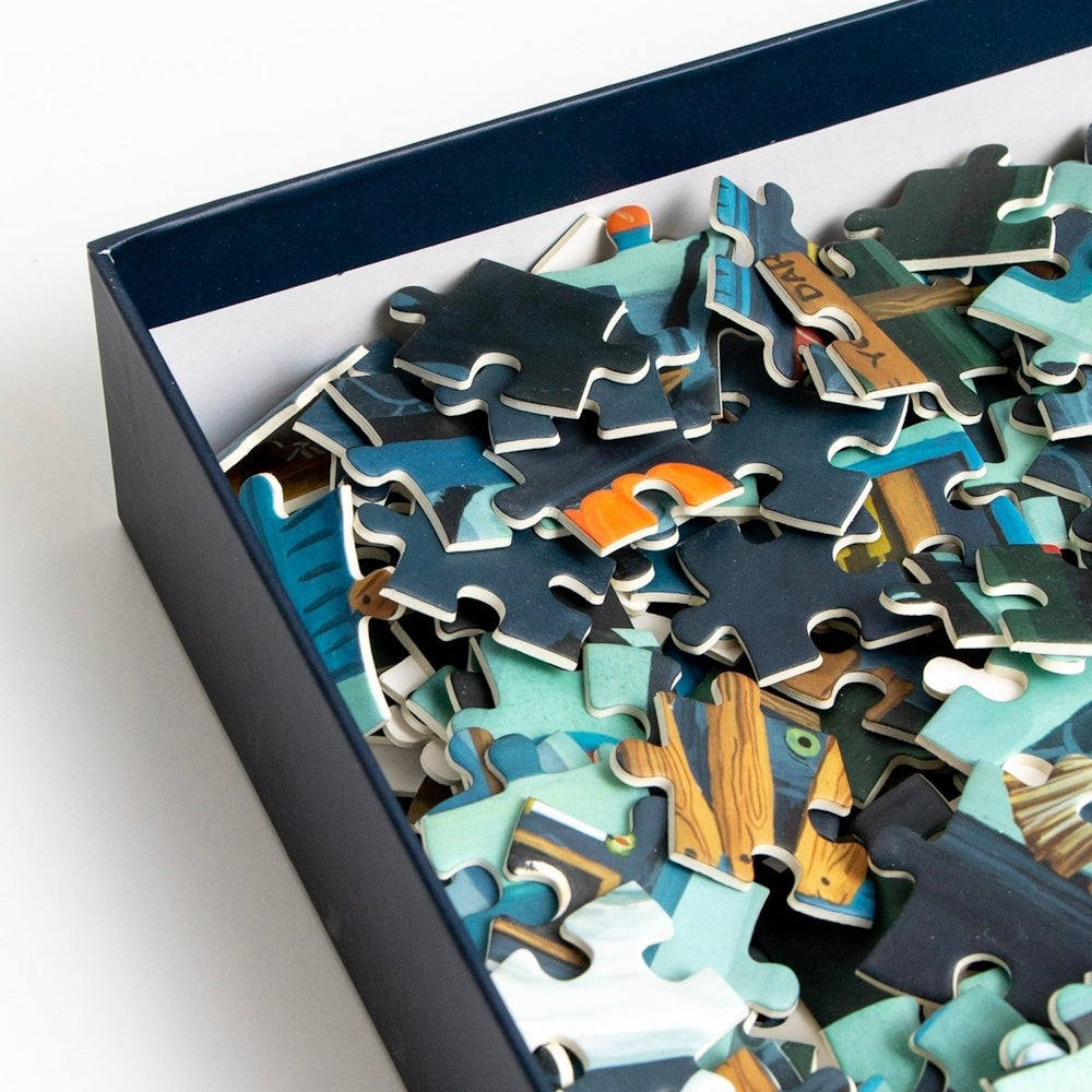 A dark blue box filled with a pile of colorful jigsaw puzzle pieces.