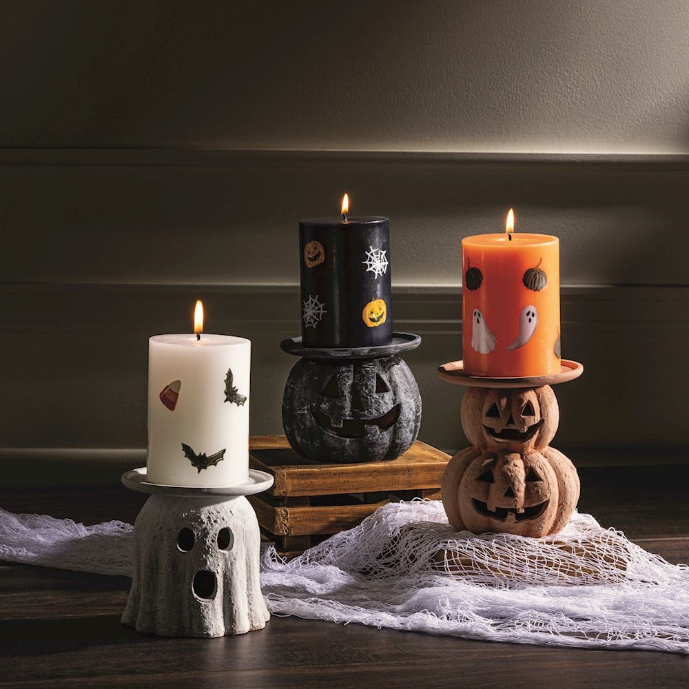 Halloween pillar candles on ghost and jack-o'-lantern candle holders.