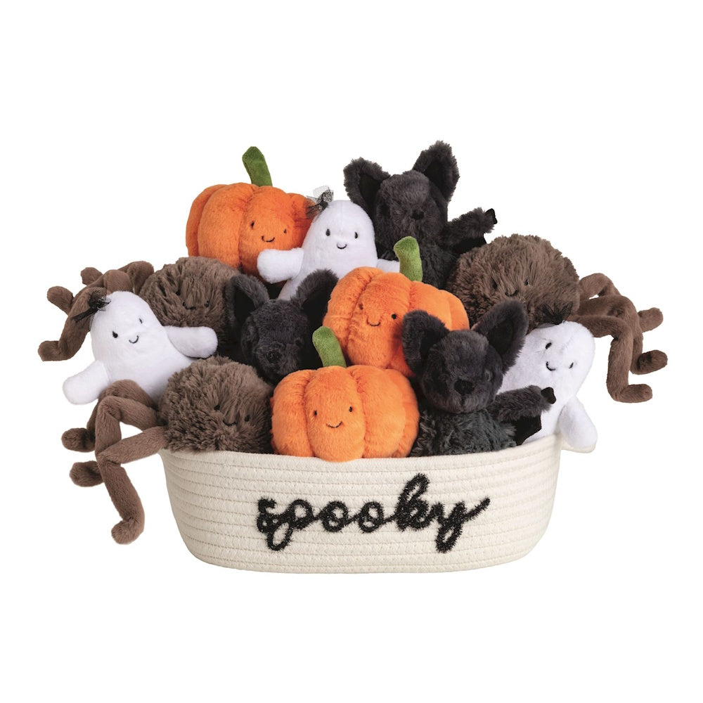 A white woven basket embroidered with "spooky" filled with Halloween plush pumpkins, ghosts, bats, and spiders.