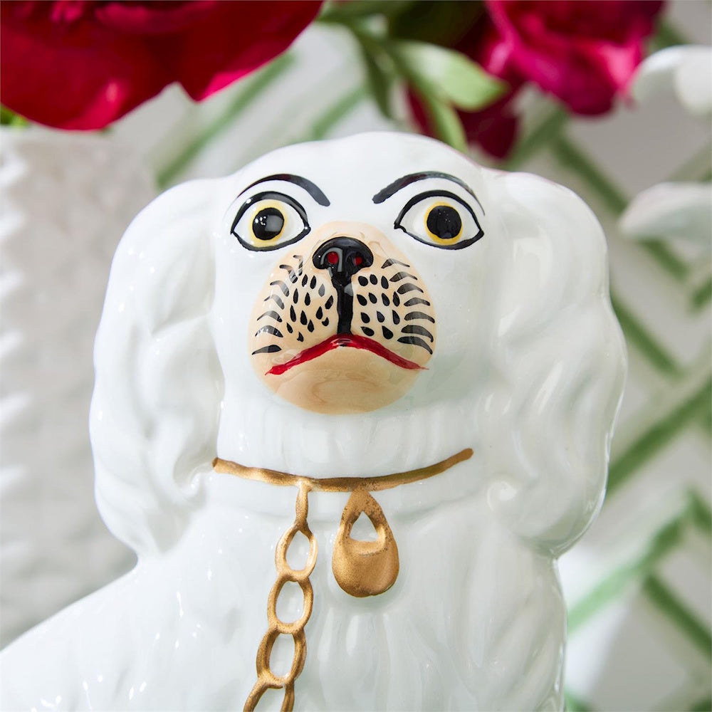 Close-up of a hand-painted white Staffordshire dog figurine with detailed facial features and a gold collar.
