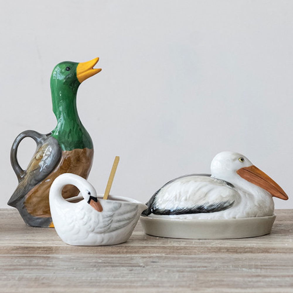 Hand-painted stoneware duck-shaped pitcher, swan gravy boat, and pelican dish on a table.