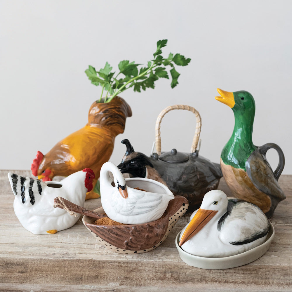 Hand-painted stoneware duck pitcher surrounded by novelty bird-shaped ceramic tablewares.