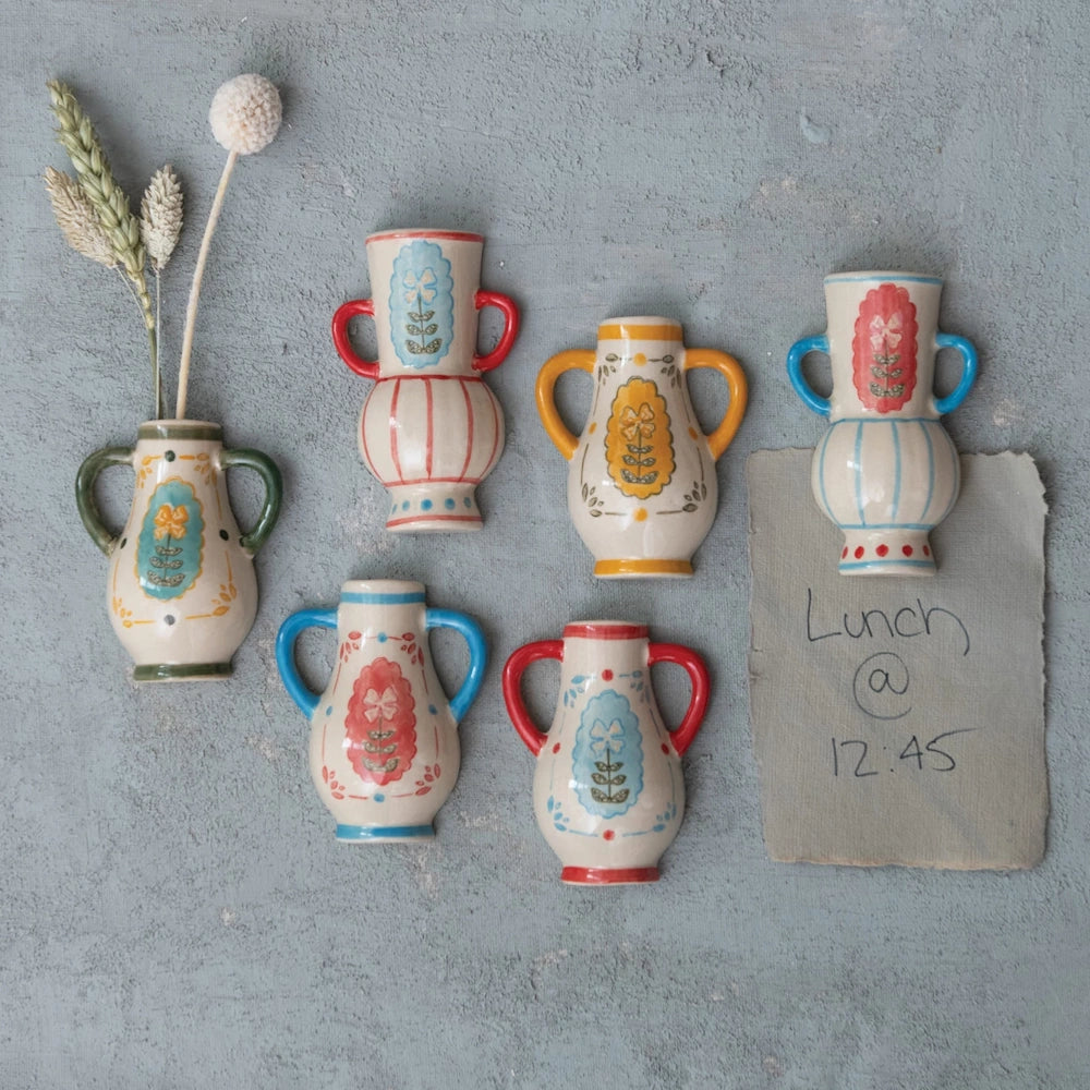 Hand-painted stoneware mini vase magnets in various colors and floral patterns displayed on a gray textured wall.