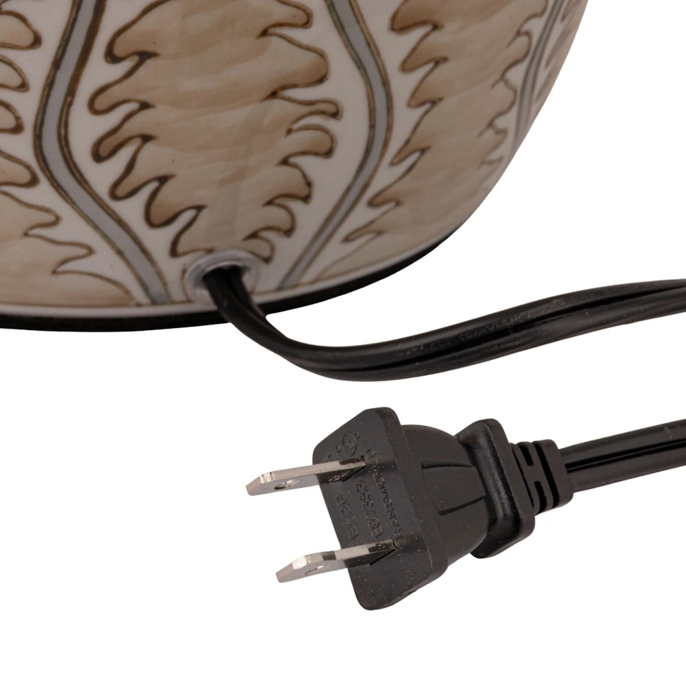 Close-up view of the black power cord and two-prong plug exiting the base of the ceramic table lamp.