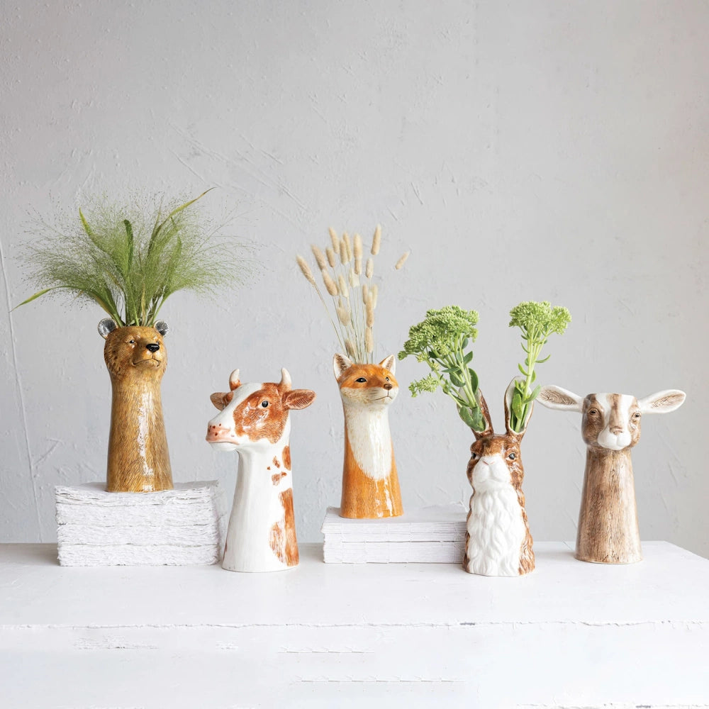 Hand-painted stoneware animal bud vases featuring a bear, cow, fox, rabbit, and goat with dried flowers and greenery.