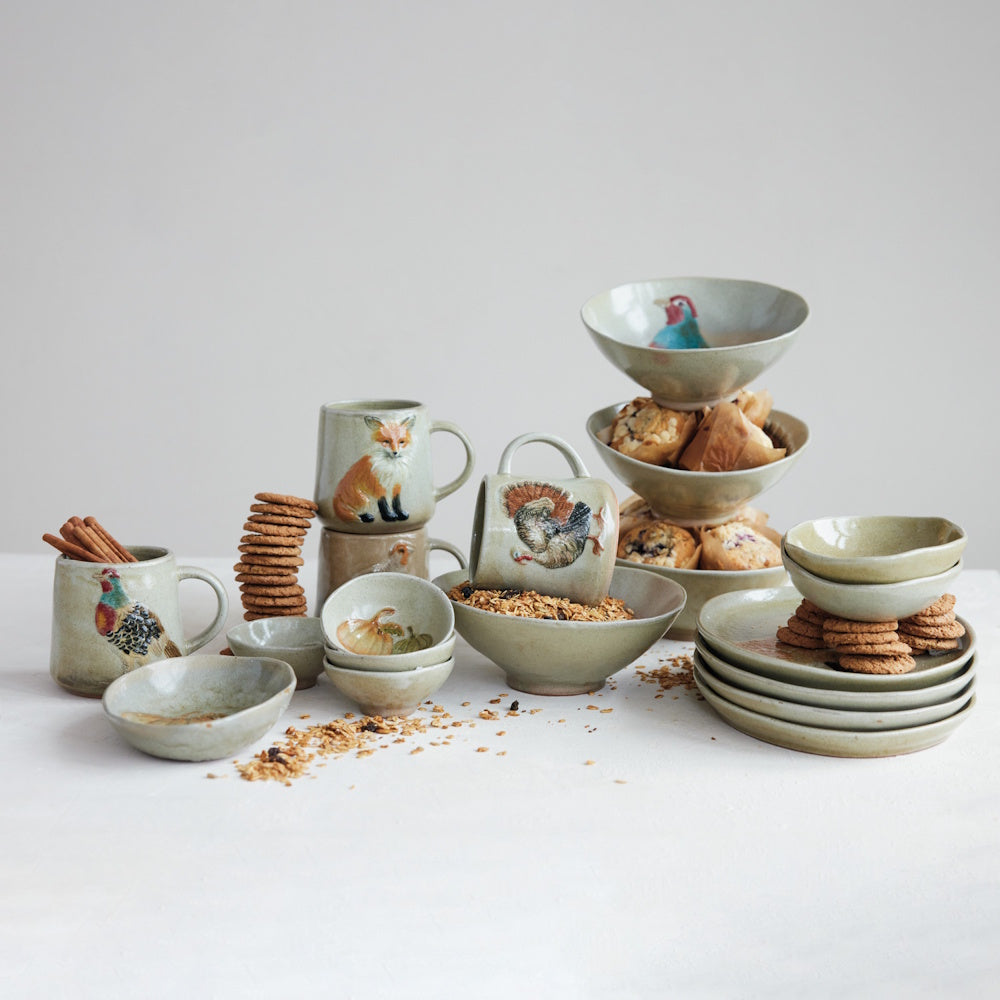 Hand-painted stoneware dishes with woodland animals and pumpkins, set with cookies and pastries.