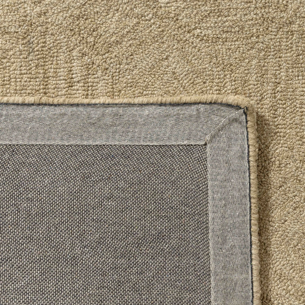 Close up of beige hand tufted rug backing showing durable woven underside and bound edge finish.