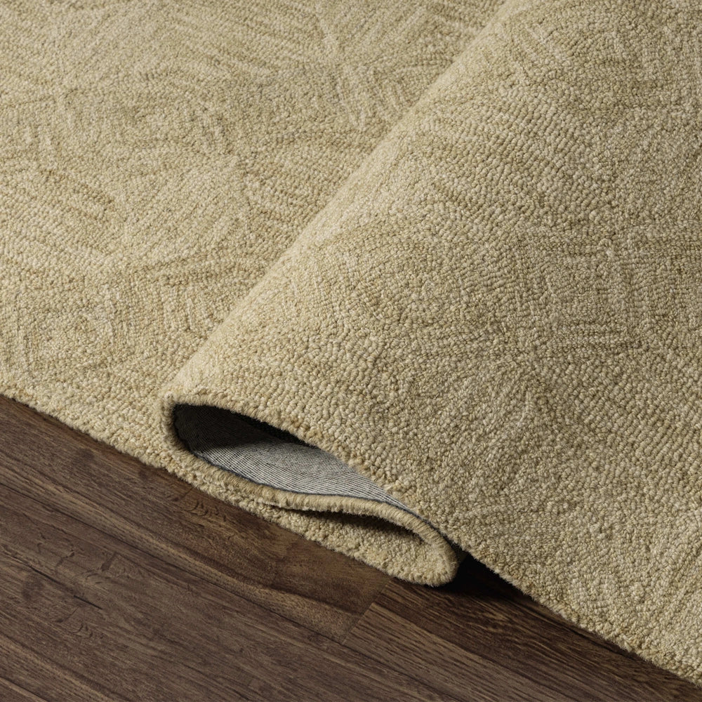 Close up of beige hand tufted rug corner showing textured geometric pattern, soft pile and folded edge detail.